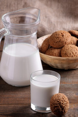 Tasty sweet oatmeal cookies with milk on a brown wooden table.