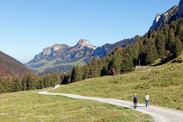 Fototapeta na wymiar Tourists hiking in sunny, last summer days, Appenzeller Sämtis valley with view of Hoher Kasten cable car station and aerial - Furgglenalp, Alpstein, Appenzell Alps, Switzerland