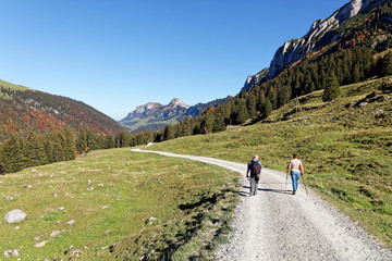 Tourists hiking in sunny, last summer days, Appenzeller Sämtis valley with view of Hoher Kasten cable car station and aerial - Furgglenalp, Alpstein, Appenzell Alps, Switzerland