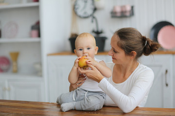 mother gives the baby apple, mother hugs son
