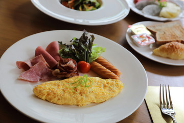 Breakfast set Omelette with sausage bacon and salad on wood background