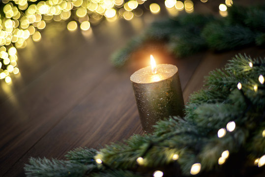 Weihnachtsstimmung mit Kerze, Tannenzweigen und Lichterketten