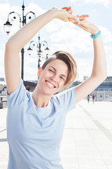 Young positive woman smiling with arms raised up