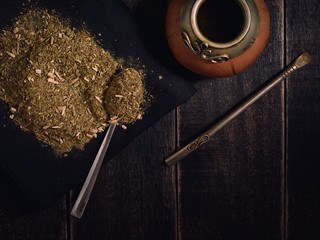 Yerba mate and calabash with bambilla on a black wooden background