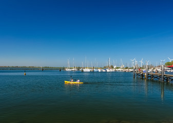 Picturesque view of two people canoeing on the sea with a bright yellow canoe at a jetty of Fehmarn island in Germany on a wonderful day with a nice blue sky. 