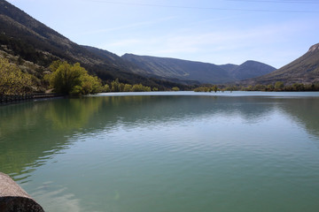 A landscape of the Arguis artificial lake in the Pre-Pyrenees mountains in the Aragon region, Spain, during a sunny day, shot from the stone railing