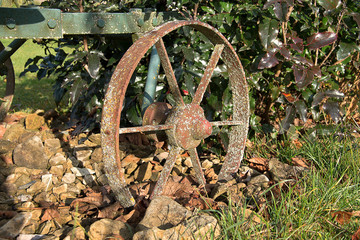 A steel wheel from an old plowed plow covered with moss.