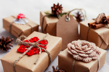 Christmas presents with hand made decorations - crocheted flower and snowflake, pine cones, vanilla pods. DIY New Year decorations for wrapped in craft paper gifts.