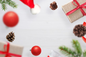 Christmas gifts, fir branches, Santa Claus's hat and cones fall on a white wooden table. Fre space...