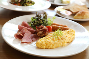 Breakfast set Omelette with sausage bacon and salad on wood background