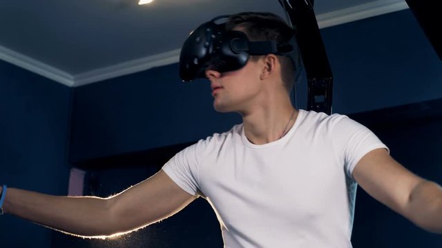 A guy in VR goggles is moving aside imaginary space in front of him. Virtual reality headset playing game 360.