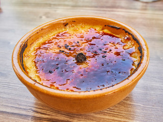 Crema Catalana or Creme Brulee in a rustic bowl, typical tavern or bistro presentation with a cinnamon stick in the middle. Traditional dessert of Catalonia, Spain, and France.