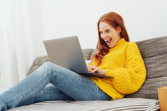 Excited you woman using a laptop at home