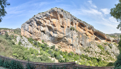 Fototapeta na wymiar A landscape of the Vero river canyon, with mountains, eroded caverns and steep cliffs, during a sunny summer day in the rural town of Alquezar, Spain