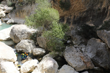People practicing canyoning in the Vero river canyon, with helmets, protections and diving suits among the rocks during summer in Alquezar, Spain