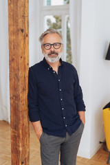 Senior man leaning against a wooden post