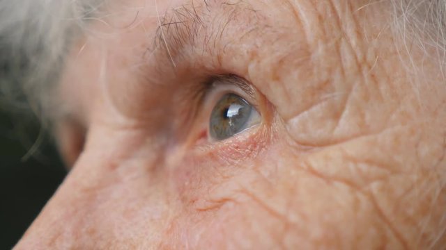 Eyes of old woman looking up and then moving from side to side. Eyes of an elderly lady with wrinkles around them. Close up Side view Slow motion
