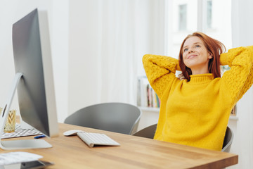 Young dreamy woman sitting in front of computer