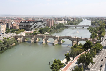 Naklejka premium A landscape of Zaragoza city, with Ebro river shores, the Stone and Iron bridges, a seen from the Pilar Catedral bell tower, Spain