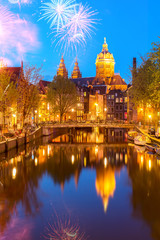 Fototapeta na wymiar Church of St Nicholas over old town canal at night with fireworks, Amsterdam, Holland