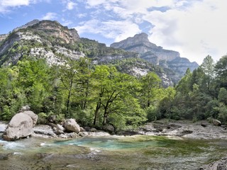 Fototapeta na wymiar The waterfalls and the rapids in the Rio Bellos canyon on the forest covered rocky mountains in the Cañon de Añisclo valley, in Aragon region, Spain