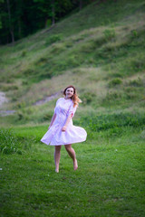 Beautiful girl in summer dress runs in the meadow.