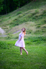 Obraz premium Beautiful girl in summer dress runs in the meadow.