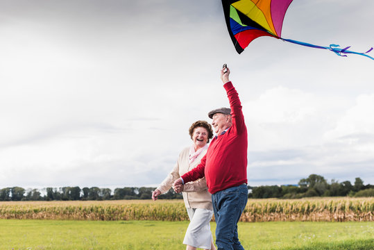 Happy senior couple with kite in rural landscape