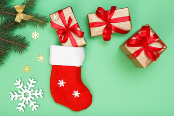 Santa's boot, gift boxes and fir tree branch on green background