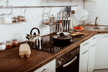 modern kitchen interior with frying pan and teapot on stove