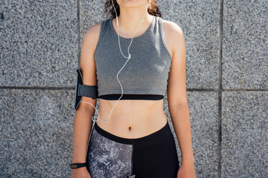 Partial view of young athletic woman wearing earbuds