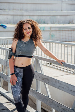 Portrait of smiling young athletic woman wearing earbuds
