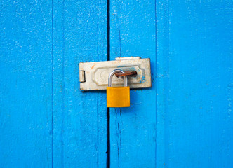 Locked padlock with chain at blue wooden door textured background