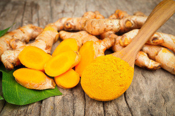 Turmeric powder in wooden spoon on old wood table. Herbal