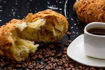 coffee pours into a Cup on a blue wooden table with coffee beans and a croissant