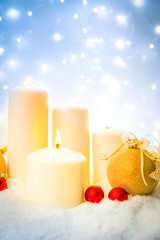 White christmas - burning advent candles in white snow, blue night with lights in background, retro toned