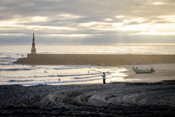 Man, Fisherman and Boat near Beacon at the Ocean