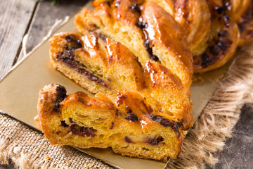 Homemade braid stuffed with chocolate and cut into pieces on wooden table. Close up	