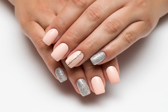 Peach manicure with silver glitters and stones, strip of crystals on long square nails close-up on a white background

