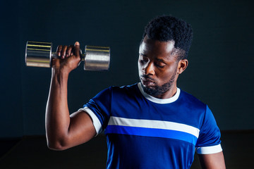 Fototapeta na wymiar muscular african american man doing push-ups exercises with weights dumbbell in the gym on a black background