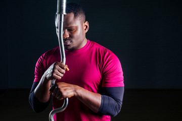 Fototapeta premium young african american man sportsman squatting sportsman exercising dumbbell T-shirt sports uniforms sport wear black background studio gym