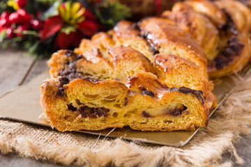Homemade braid stuffed with chocolate and cut into pieces on wooden table. Close up	
