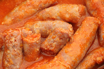 A detail of homemade sausages stew in spices and tomato sauce to eat with polenta, a typical Italian dish