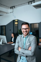 Happy office worker standing in his office.
