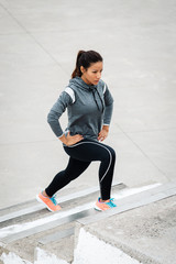 Leg lunges exercise on stairs. Fitness woman working out in the city.