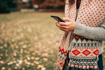 Text messaging outdoors in the autumn. Close-up.