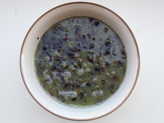 Recently stomped red grapes must in a white ceramic bowl on a white surface, an important step in...