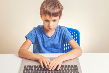 Concentrated boy typing on laptop computer