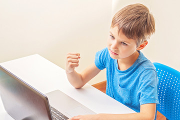 Kid playing computer games with laptop at home
