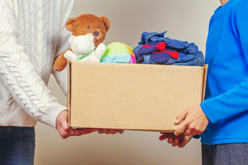 Donation concept. Donate box with clothes, books and toys in family members hand
